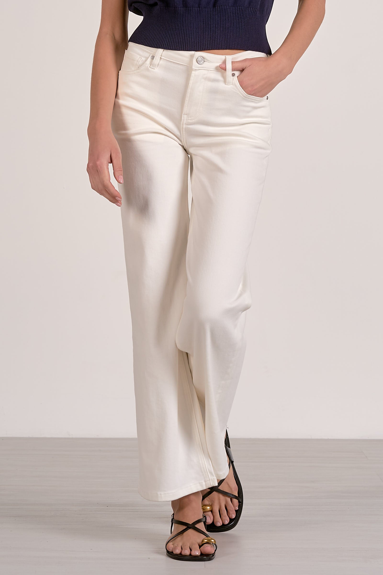 Person wearing white pants and a navy top on a plain background